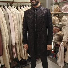 A happy client trying on his custom black embroidered sherwani in my studio. The smile on his face says it all.