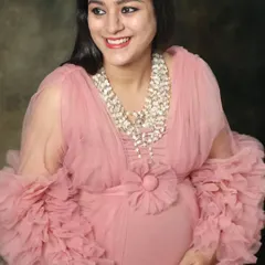 A beautiful close-up of a smiling mom-to-be in a frilly pink gown. Her happy expression and the soft texture of the dress create a joyful and feminine portrait.