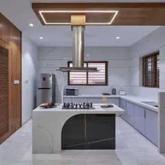 We designed this modern kitchen around a stunning marble island with an integrated cooktop, making it the true heart of the home. The combination of sleek, light-grey cabinetry, a stainless steel chimney, and warm wood accents creates a perfect balance of function and style.