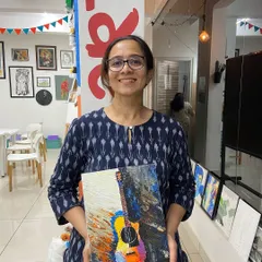 A participant proudly displays her vibrant guitar painting created with a palette knife. This technique adds amazing texture and depth to the artwork.