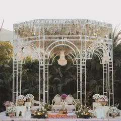 Set against the lush greenery of Udaipur, this elegant white mandap features a delicate, open-air structure with a canopy of hanging white florals and a central chandelier, creating a light and airy feel.