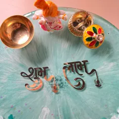 This shot focuses on the traditional elements of the pooja thali, including the "Shubh Labh" text, a Ganesha idol, and holders for kumkum and a diya.
