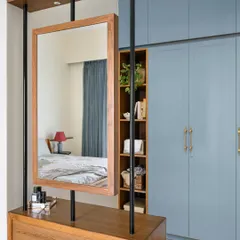 A royal blue walk-in wardrobe from the 'House of Kismish' project, artfully partitioned by a suspended vanity mirror. This design adds a touch of luxury and drama to the bedroom.