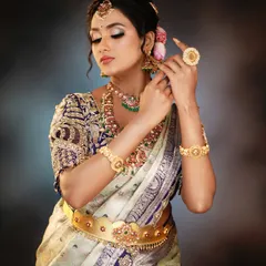 A side view of an elegant bridal updo, adorned with fresh flowers and traditional jewelry. The hairstyle is designed to be secure and beautiful from all angles.