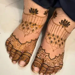 An elegant foot design with hanging lotus motifs that look like a delicate payal or anklet. The toes are covered in intricate floral patterns.