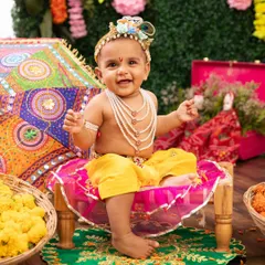This happy little Krishna is ready for the Janmashtami festivities. The colorful fabrics and traditional props complete this adorable themed look.