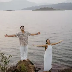 A joyful moment of freedom, with the couple spreading their arms wide by the lakeside, embracing the beauty of the natural landscape.