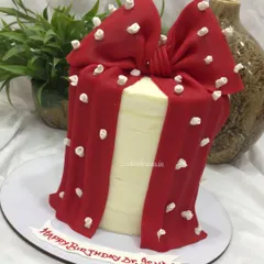 A different angle of the red bow cake, showing the texture and flow of the fondant drape.