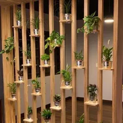 This wooden structure acts as both a room partition and a vertical garden. The open slats maintain a sense of space, while the built-in shelves are perfect for displaying a collection of small potted plants.