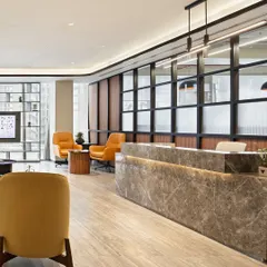 The reception area of a modern office, featuring a marble-clad desk and warm, inviting seating. This space is designed to be the perfect first touchpoint, blending professional aesthetics with a sense of comfort and hospitality.