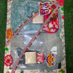 A colorful Holi hamper with clothes for a couple, along with gulal and other festive items. The packing is decorated with bright, multicolored lace.