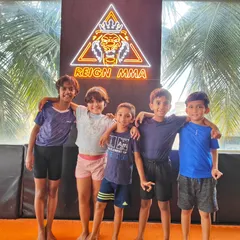 Our Kids MMA class posing in front of the Reign MMA logo. We create a positive and encouraging environment where children aged 6-12 can begin their martial arts journey.