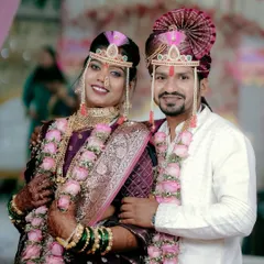 A classic portrait of a smiling Maharashtrian bride and groom in their wedding attire, complete with mundavalya and traditional jewelry.