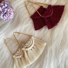 My geometric triangle earrings with a macrame twist. These statement pieces feature a fan of knotted fringe hanging from a gold-toned triangular frame, available in both a deep maroon and a natural off-white.