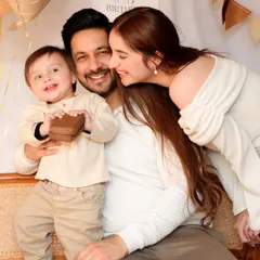 Pure happiness captured during a first birthday photoshoot. This candid shot shows the family sharing a laugh, with the baby boy holding a small gift, perfectly capturing the joy of the moment.