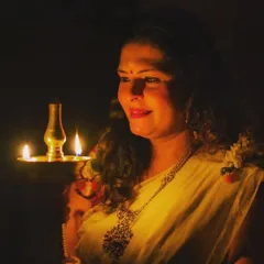 A beautifully lit portrait holding a traditional lamp, wearing a Kerala saree for Onam.