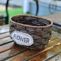 A simple, dark brown woven basket-style planter, perfect for holding flowers or small potted plants on a tabletop.