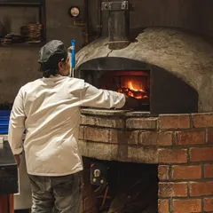Tending the flames is an art. Our chefs maintain the perfect temperature in our custom-built brick ovens, ensuring every pizza that comes out is consistently delicious.
