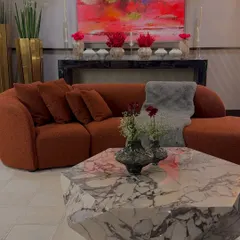 A beautifully styled living room, where our floral arrangements complement the client's bold taste in furniture and art. The red and orange tones are carried from the sofa to the flowers.