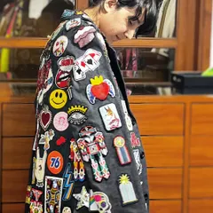A closer look at the detailed patch and embroidery work on the custom trench coat. Each patch, from the sacred heart to the smiley face and playing cards, was chosen and placed to build a rich visual narrative.