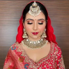 A close-up of a heavy Kundan and pearl choker set against a traditional red bridal lehenga. This rental includes the choker, oversized jhumkas, and a large maang tikka.