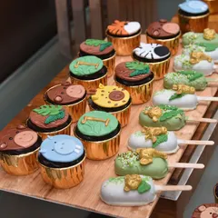 The details make the theme. This shot highlights the variety in the jungle dessert set, showing off the hippo, giraffe, and zebra cupcake toppers alongside the green and gold jungle-leaf cakesicles.