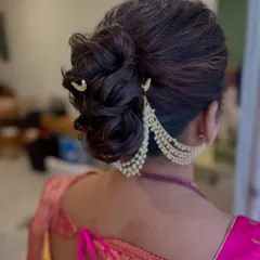 A side view of the braided bun, showcasing the beautiful texture and the way the pearl accessory drapes gracefully around the updo. This is a perfect style for a reception or engagement.