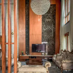 The entertainment zone in the living room is framed by floor-to-ceiling wood and marble panels. This composition creates a sophisticated backdrop for the television, integrating technology seamlessly into the luxurious decor.
