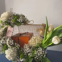 A side view of the luxurious floral cage arrangement. This angle shows the lush combination of white chrysanthemums, baby's breath, green button mums, and fresh ferns that create the base.