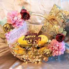 A unique anniversary hamper featuring a basket of fresh mangoes, a beautiful saree, and a personalized card. This gift is a perfect blend of tradition and personal taste.