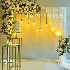 A modern and minimalist decor idea, this setup combines a cascade of yellow and white flowers with hanging Edison bulbs. It’s a chic backdrop for a cake-cutting ceremony or engagement.