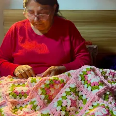 Here I am adding the finishing touches to a pink and green granny square blanket. Each piece is made with immense focus and love, ensuring every stitch is just right.