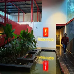 An evening view of the SARITHA SERENE office, where the illuminated signage and its reflection in the water create a dramatic effect. This demonstrates our approach to integrating lighting as a key component of architectural identity.