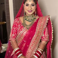 A happy Punjabi bride in a beautiful pink lehenga with green jewelry. The makeup is kept bright and joyful to match the wedding atmosphere.