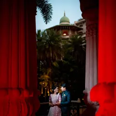A dramatic and romantic reception photo, framed by red pillars, capturing the couple in an intimate moment.