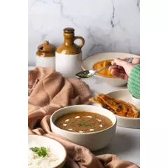 A moment captured as ghee is drizzled over a bowl of dal. This action shot adds a dynamic and appetizing element to the scene, highlighting the richness of the dish.