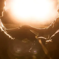 The sun dips low, casting a golden flare as the couple holds each other close. This silhouette captures the raw, romantic feeling of being alone together in nature.