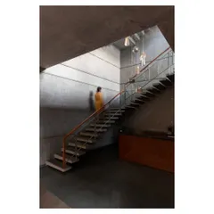 Ascending the staircase, the play of light and shadow on the board-formed concrete walls creates a powerful, atmospheric experience. The scale of the space is both grand and grounding.