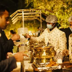 My service staff, in uniform and following all hygiene protocols, serving guests at a wedding buffet. I ensure my team is professional, friendly, and efficient.