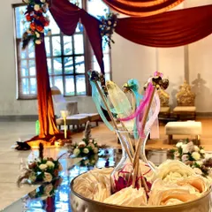A close-up of the decorative details along the aisle, with colorful wands in a vase, set against the backdrop of the beautifully draped mandap.