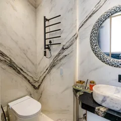 This view showcases the striking veining of the marble walls, which creates a powerful visual statement. The minimalist design of the smart toilet and fixtures allows the natural beauty of the stone to shine.