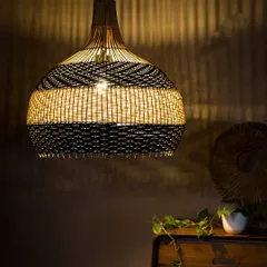 This two-tone pendant, featuring bands of black and white, is shown illuminated. The light glows warmly through the white section while being elegantly contained by the black, creating a striking visual balance.
