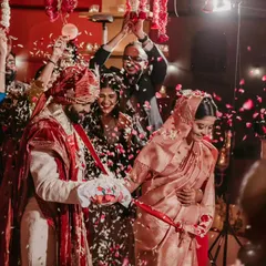 A candid moment during the pheras, with family members joyfully showering the couple with petals.