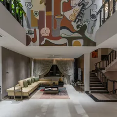 A double-height wall is not a challenge; it's a grand canvas waiting for its story. In this 'House of the Rising Sun' project, we created a massive mural that becomes the architectural soul of the home, connecting two floors with a single, continuous narrative of abstract faces and musical forms under a sunlit skylight.