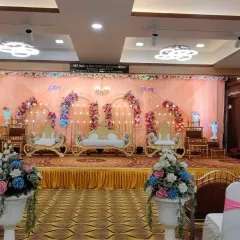 A traditional stage setup for a Maharashtrian wedding at Devadiga banquet hall. The decor features multiple golden chairs for family rituals and a colorful floral backdrop, keeping the focus on the ceremony.