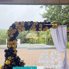 A sophisticated black and gold theme for a 48th birthday. This outdoor setup features a balloon arch and large marquee numbers.