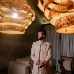 The groom looking dapper under the warm glow of rustic chandeliers. We use creative lighting to create moody and stylish portraits.