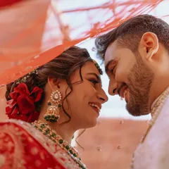 A joyful and intimate moment between a Gujarati couple, captured under the bride's traditional Bandhani dupatta.
