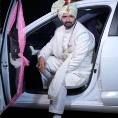 Arrive in style. This groom is wearing a classic white embroidered sherwani, complete with a safa (turban) and mala (necklace), which are also available for rent to complete your look.