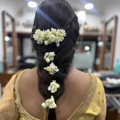 A classic South Indian bridal hairstyle. This traditional thick braid is beautifully adorned with fresh jasmine flowers, or gajra, creating a timeless and fragrant look for the wedding day.